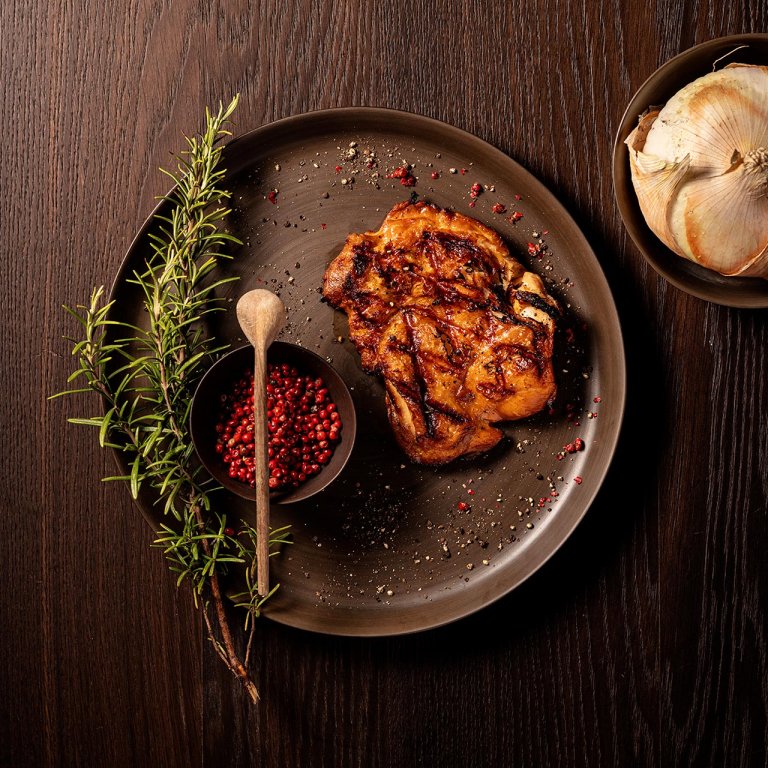 Hähnchenbrust mit Rosmarin-Dekoration, Schüssel mit Gewürzen und Holzlöffel