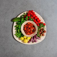 Caponata con decoración de pimientos amarillos y verdes, tomates y berenjenas