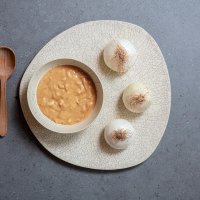 Sopa de cebolla con cuchara de madera y tres cebollas blancas enteras