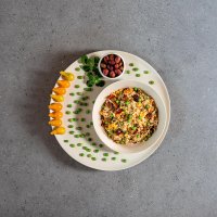 Ensalada de arroz con decoración de tomates, guisantes y aceitunas